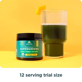 Ancient Nutrition Poudre Super Greens Bio Mangue 159g près d'une bouteille d'eau