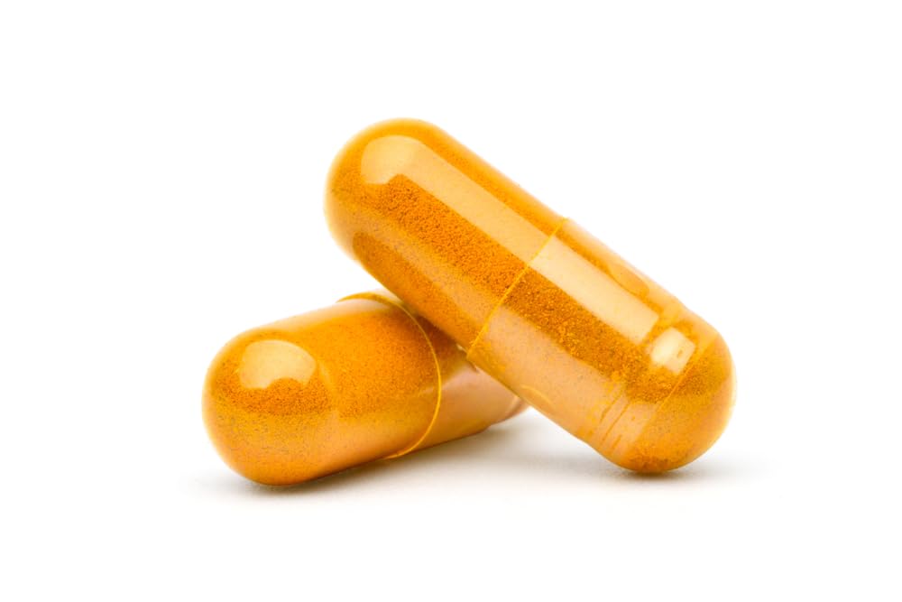 Antler Farms Curcuma capsules on a wooden table with herbs