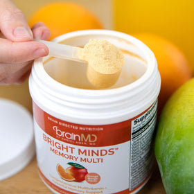 BrainMD Bright Minds Memory Multi 222g poudre à côté d'un smoothie
