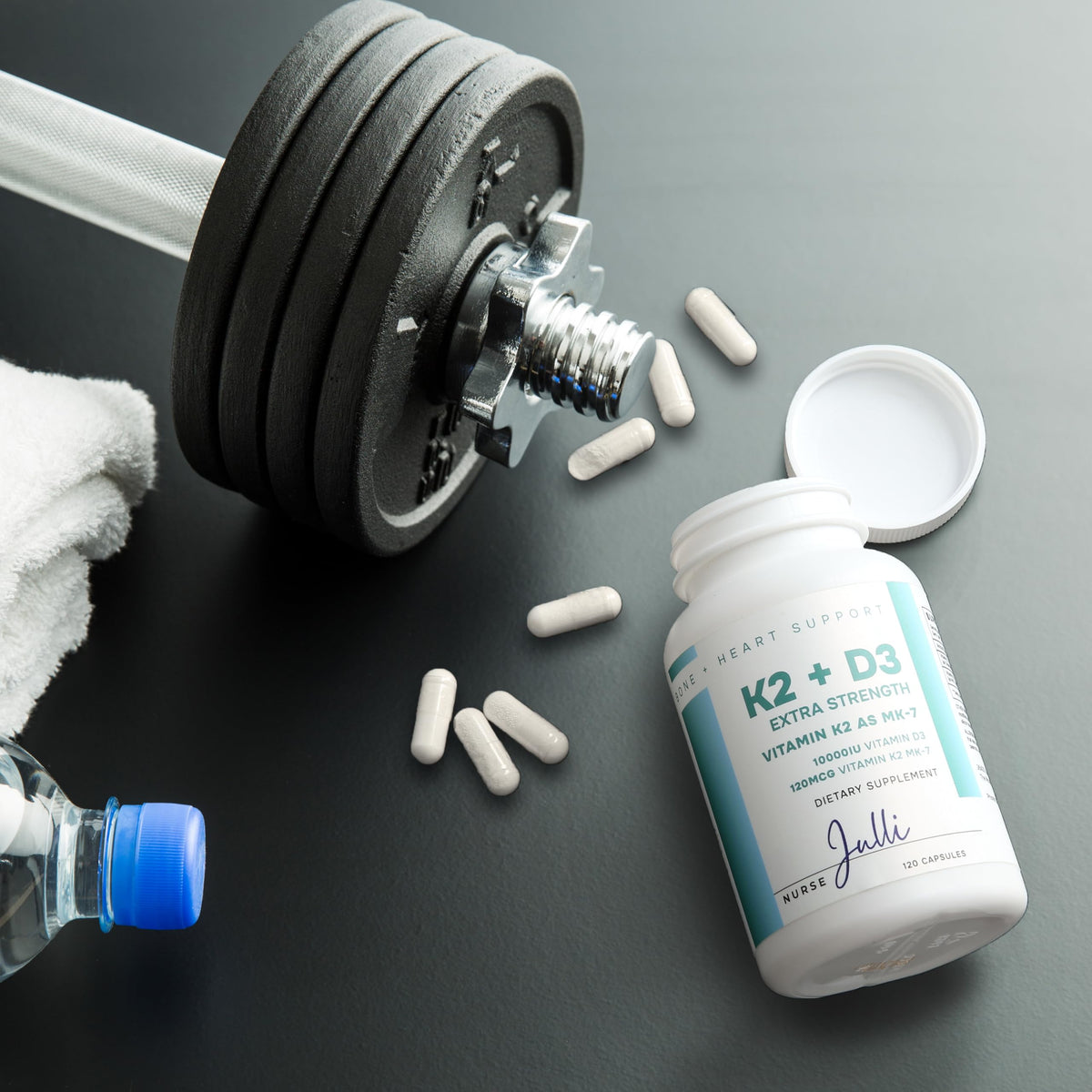 Capsules de Nurse Julli K2 + D3 à côté d'un verre d'eau