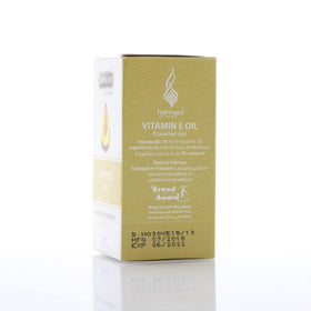 Flacon d'huile de vitamine E Hemani avec goutte sur une table en bois