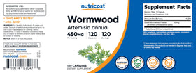 Flacon de capsules d'armoise Nutricost sur un bureau, avec des plantes en arrière-plan