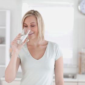 Flacon de Ecological Formulas Tri-Salts 200 g sur une table avec un verre d'eau