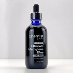 Flacon de méthylène bleu avec dosage à côté d'un verre