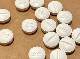 Flacon de pilules placebo Zeebo ouvert avec plusieurs pilules à l'extérieur