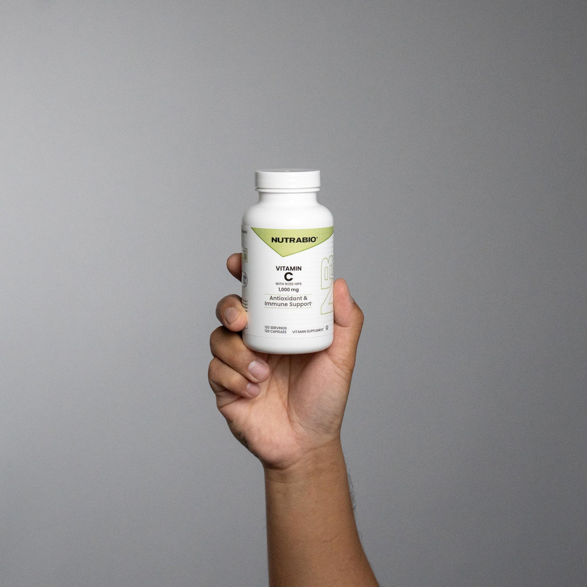 Flacon de Vitamine C NutraBio avec églantier sur une table en bois