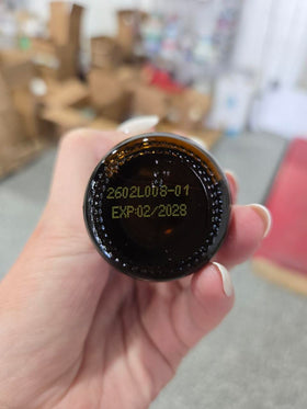 GlycoPezil 60 mL avec des gouttes sur une surface blanche