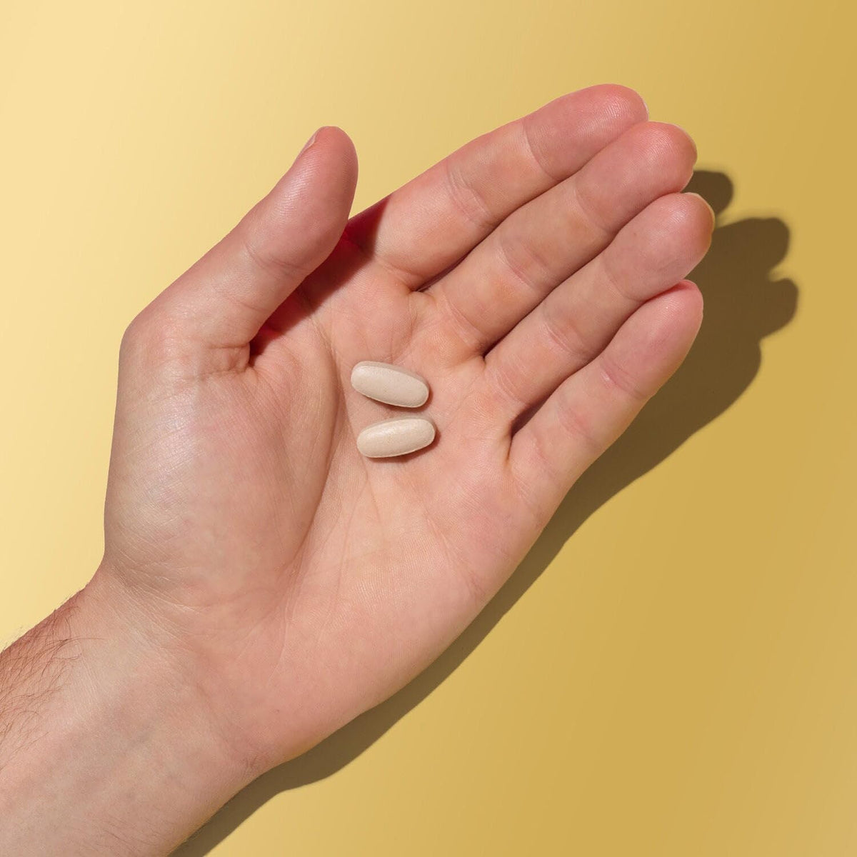 GNC Mega Men Multivitamin caplets sur une surface blanche