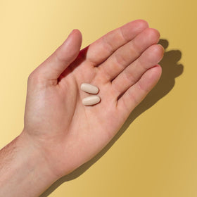 GNC Mega Men Multivitamin caplets sur une surface blanche