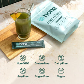 Hona Fiber + Greens Poudre 431g sur une table avec fruits