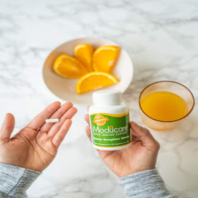 Moducare Complément Alimentaire 180 Capsules Végétariennes avec une main tenant la boîte