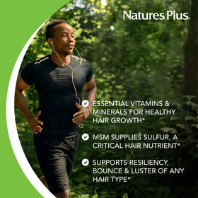NaturesPlus Ultra Hair Plus comprimés avec une main tenant un comprimé