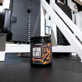 NutraBio Intra Blast Poudre BCAA en poudre près d'un verre d'eau