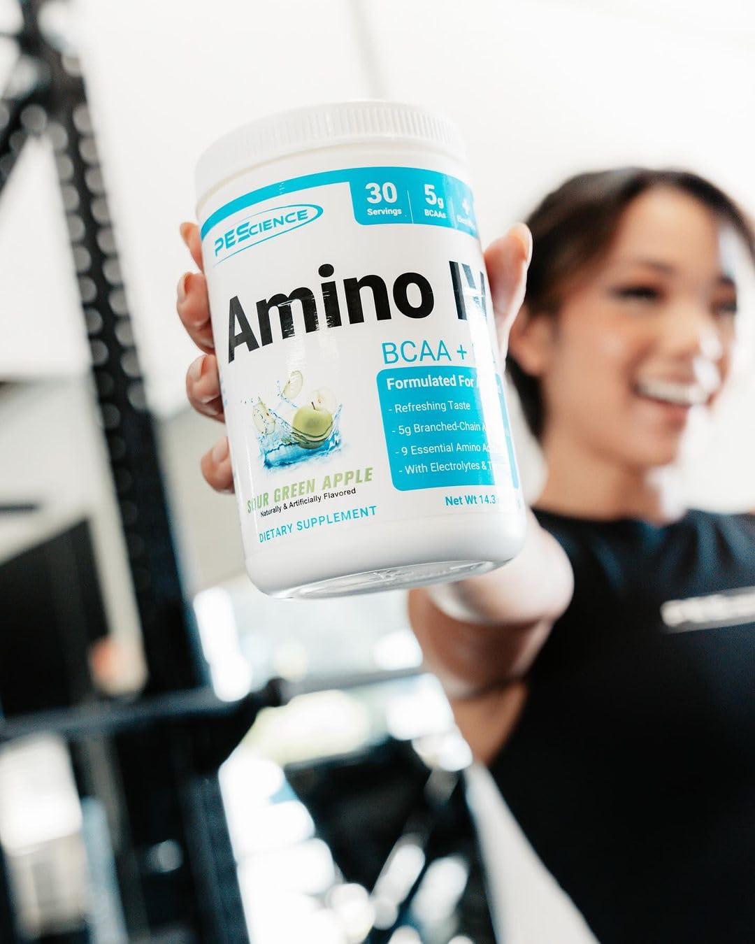 PEScience Amino IV Poudre BCAA & EAA Framboise Raisin sur une table de gym