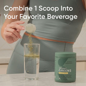 Poudre de super-aliments bio Sports Research 220g à côté d'un verre d'eau