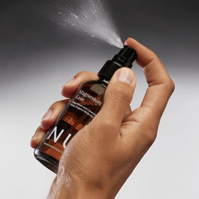 Spray de Magnésium The Nue Co avec des fleurs de lavande en arrière-plan