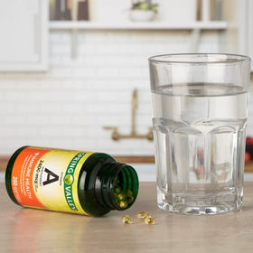 Spring Valley Vitamine A 2400 mcg, gélules à côté d'un verre d'eau