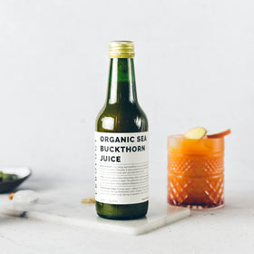 Verre de jus de baies de sorbier Erbology avec des fruits en arrière-plan